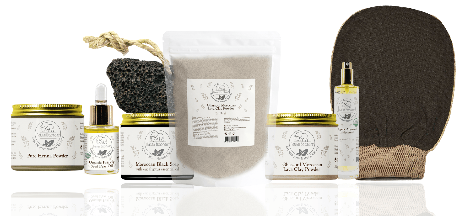 A variety of organic skincare essentials by Natural Elephant, including prickly pear seed oil, argan oil, henna powder, Moroccan black soap, and Ghassoul clay, alongside a pumice stone and exfoliating glove.